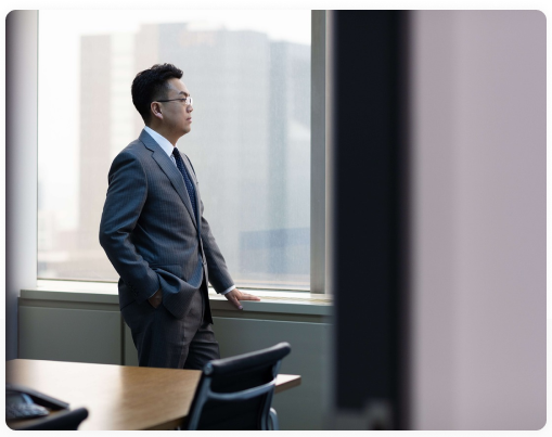 Man in a suit looking out of an office window